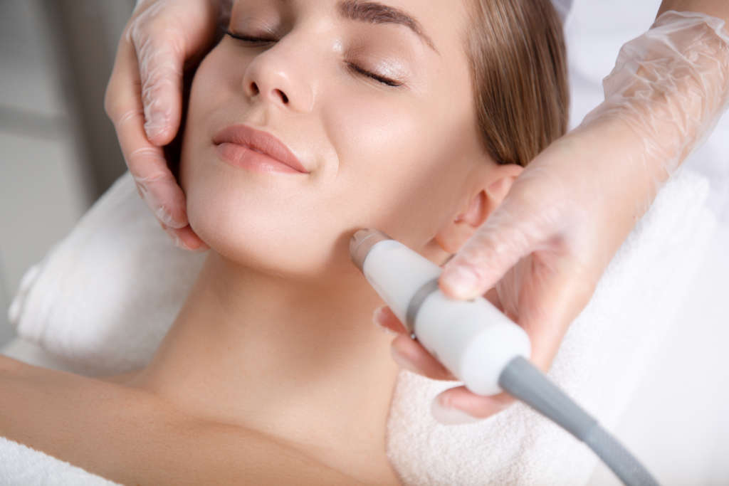 Calm young woman getting cavitation rejuvenation skin treatment