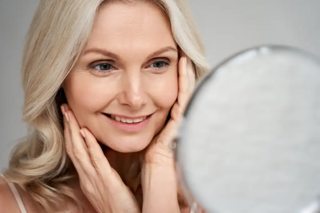 A smiling woman admires her youthful appearance after availing rejuvenating treatments at a medical spa.