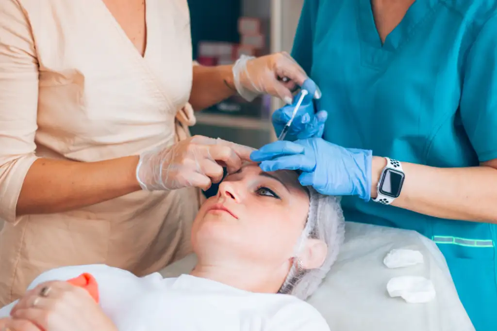 A patient receiving a wrinkle relaxers session administered by two medical professionals.